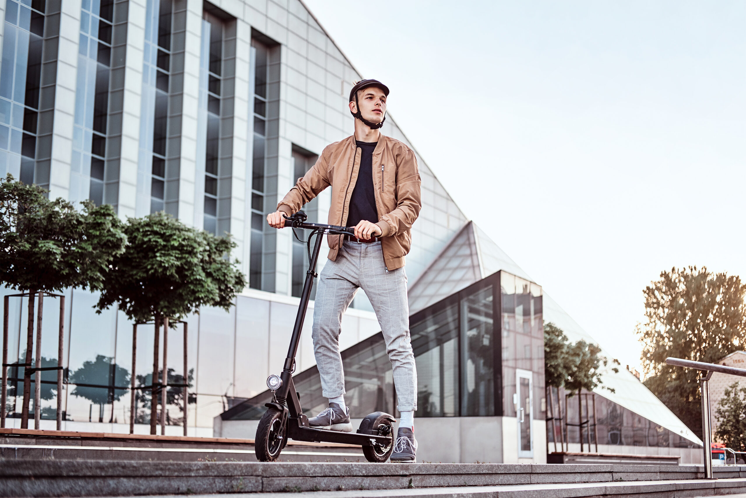 Young man driving an electric scooter and wearing a helmet