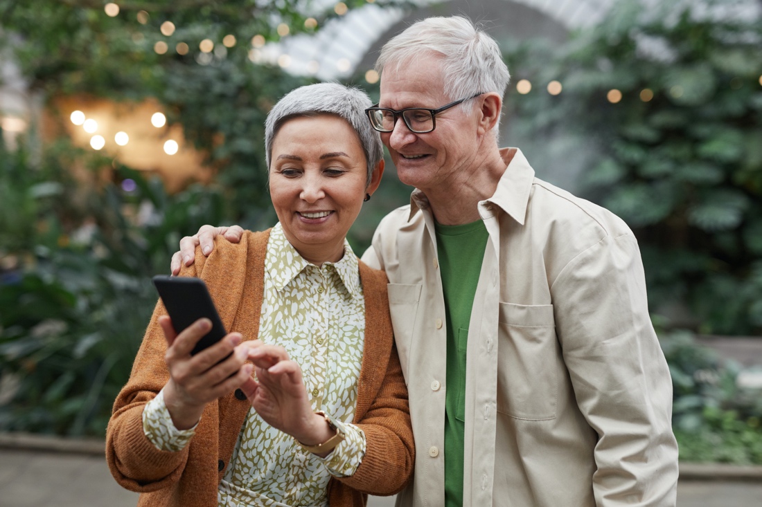 Elderly couple smiling and looking at smartphone
