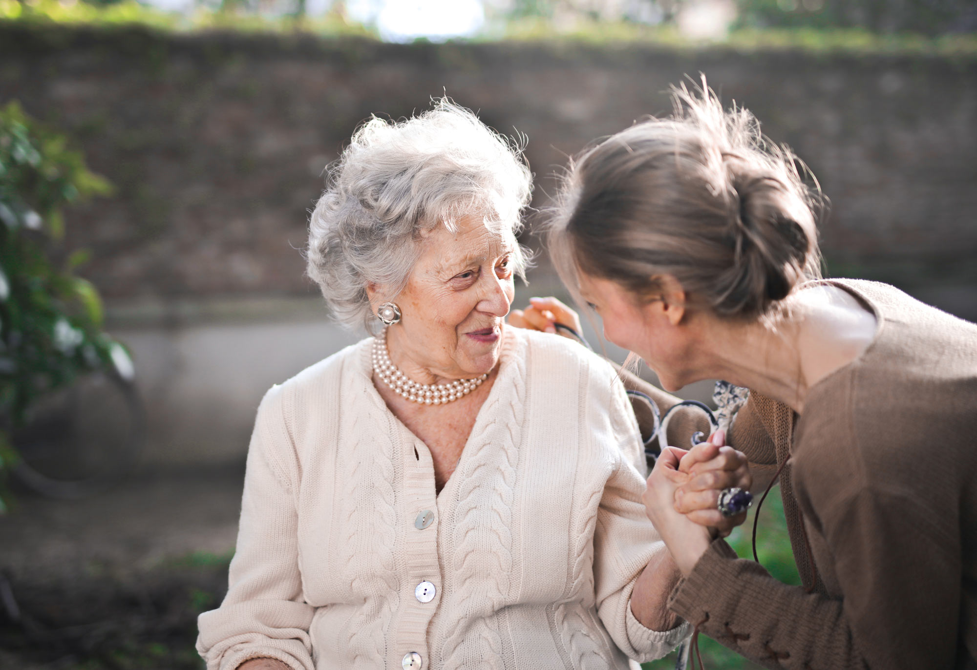 Elderly woman holding hands with younger woman