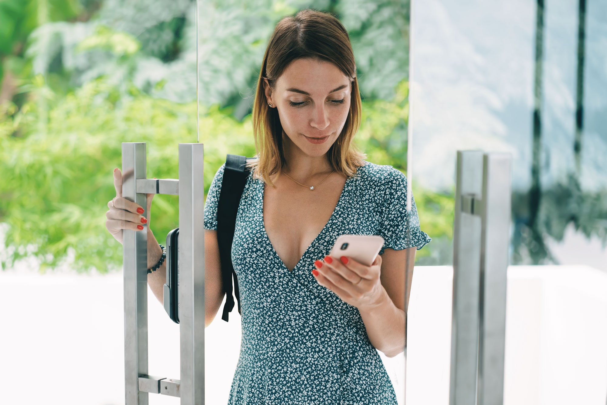 Young woman checking her smartphone while entering a building