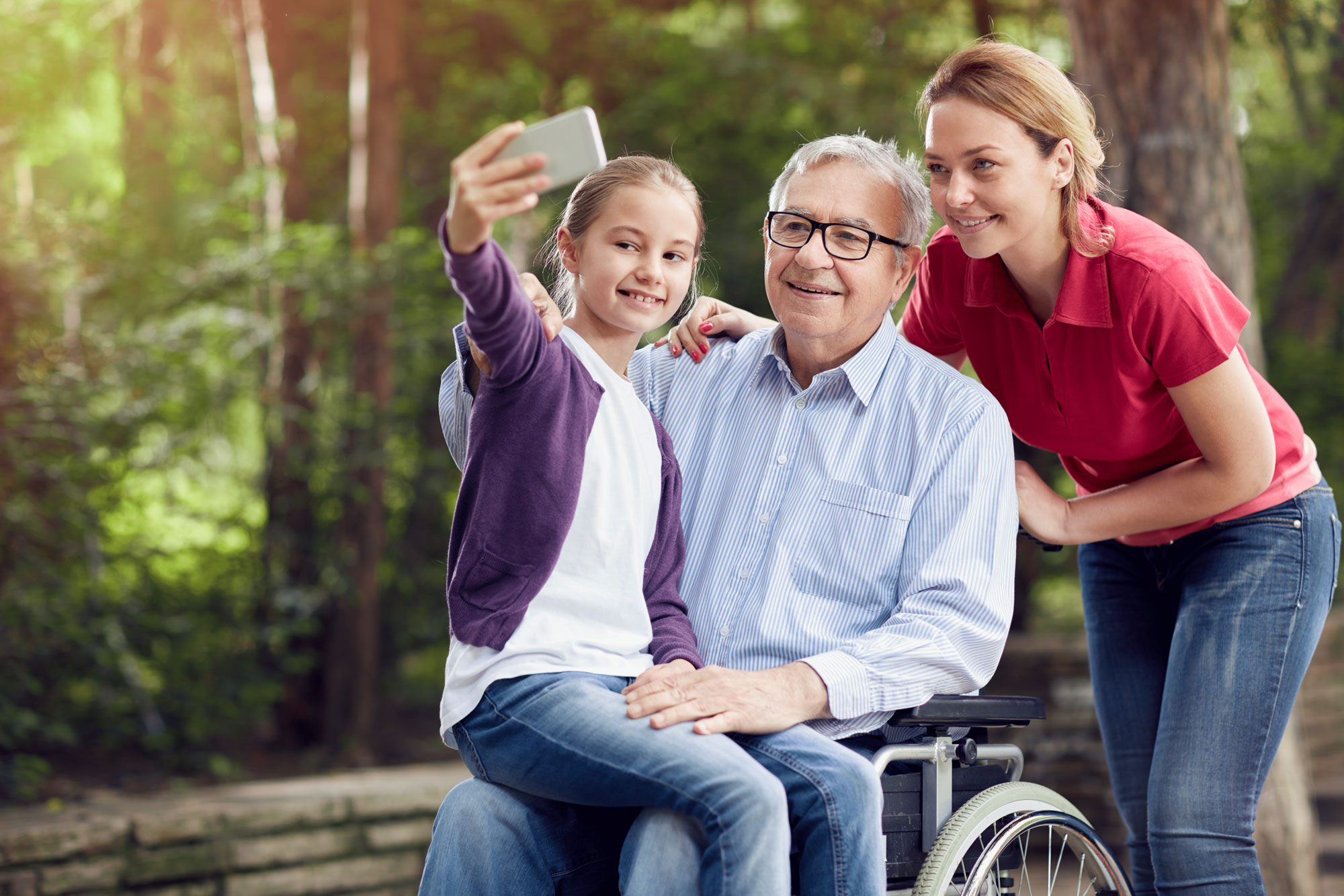 Young girl, old man, and middle-aged woman taking a selfie with the young girl's smartphone