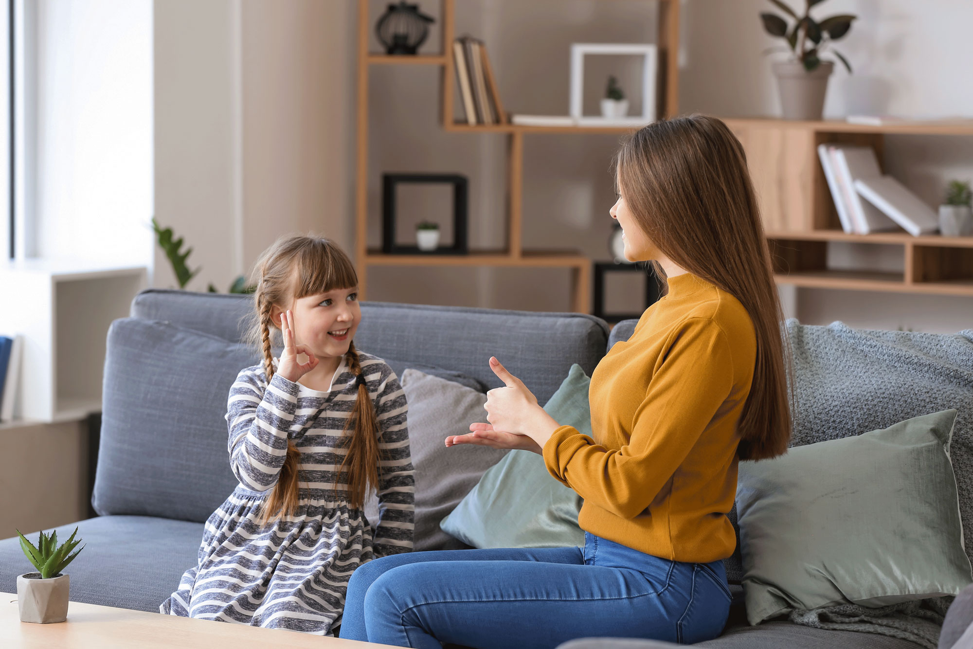 Little girl with younger woman practicing sign language